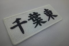 白の生地に高校の校名を黒糸で大きめに刺繍した文字ワッペンの加工事例。