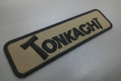 トンカチを想起させる変わったオリジナル書体で刺繍した文字ワッペンの制作事例。生地はアーバンツイル。カラーはライトベージュ。