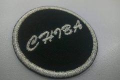 小さめの円形の文字ワッペン。黒のツイル生地に銀糸で県名を刺繍した作品事例。