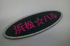黒のツイルキイをベースにショッキングピンク糸で文字を刺繍。、外周フチは銀糸でアクセントをつけた、文字ワッペンの加工事例。