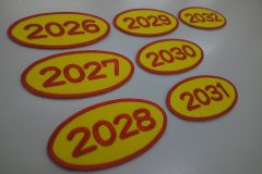 2026～2032の数字を赤糸で加工した、文字ワッペン7枚の作品事例。形状は楕円形。