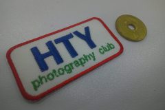 白のアーバンツイル生地に青と緑、赤の三色で写真クラブのクラブ名を刺繍した、文字ワッペン。