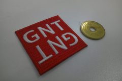 赤の生地に白文字で上下に反転した形で刺繍した、文字ワッペンの制作事例。