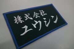 黒のツイル生地に白糸で会社名を刺繍。外周フチはロイヤルブルー糸で仕上げた作品。