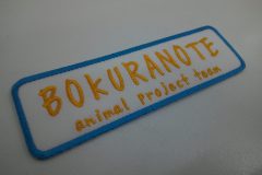 白生地に橙色の糸で文字を刺繍。手書き風のフォントが特徴的な作品。