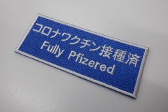 青生地をベースにワクチン接種済みであるメッセージを刺繍した、文字ワッペンの制作事例。