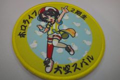 円形のプリントワッペン。中心には元気な女の子のキャラクターを加工した制作事例。