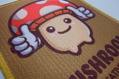 大きめに加工されたキノコのキャラクターデザインが可愛らしい、プリントワッペンのアップ。サブリックスクロスを使用。