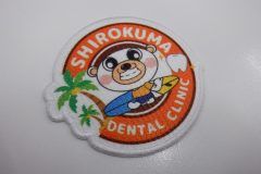 可愛らしいクマのキャラクターがトレードマーク。歯科医院のロゴが加工されたプリントワッペンの制作事例。