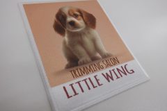 子犬のイラストと“TRIMMING SALON LITTLE WING”の文字が入った長方形のオリジナルプリントワッペンの制作見本。