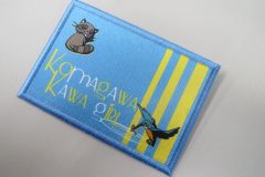 青地のワッペンにタヌキと鳥、黄色いストライプ、『Komagawa Kawa Girl』の文字が加工されたオリジナルプリントワッペンの制作事例。