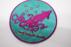 エメラルド地にピンクと黄色の糸で刺繡された目を引くオリジナル刺繡ワッペンの制作実績。