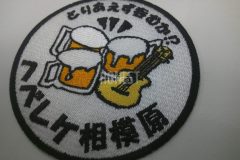 白地に黒・白・オレンジ・黄色の糸で刺繍されたサークルロゴのオリジナル刺繡ワッペン。