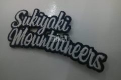 文字だけの構成で印象的なグループロゴのオリジナル刺繡ワッペンの制作事例。複雑な外周を見事にカットした高度なヒートカット技術もうかがえる。