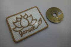 ５円硬貨のタテ寸1.2倍ほどのミニマムな白生地に金糸で蓮の花をモチーフにした花が刺繍されたオリジナルワッペンの制作事例。