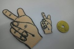 ペールカラーのフェルト生地をベースにピースサインをモチーフにしたオリジナル刺繡ワッペンの制作事例。ししゅう屋HONESTは５円玉ほどの小さなワッペン加工も得意です。