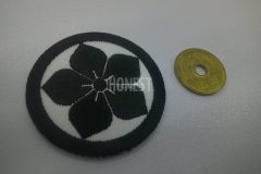 白のアーバンツイル地に黒糸のみで紋様をイメージさせるモチーフを加工した刺繍ワッペンの制作見本。