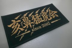 黒のアーバンツイルにプロ野球チームの応援団のロゴをブロンズカラーの刺繍糸で加工した、オリジナル刺繍ワッペンの制作事例。