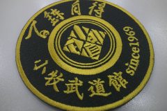 黒のツイル生地にマットゴールド単色で武道館名とそのロゴを刺繍加工したオリジナルワッペン。