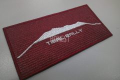 エンジ色の生地に白色で霊山御嶽のシルエットと競技名を刺繡した、オリジナル刺繡ワッペンの制作事例。