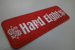 赤色のクロス生地に白色でブランド名とペイズリー柄の模様を刺繡した、オリジナル刺繡ワッペンの制作事例。