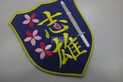 剣道の竹刀と桜のイラストを刺繡した、剣道教室のオリジナル刺繡ワッペン。漢字の一部を桜の花びらにしたデザイン。
