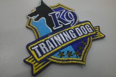 リボンと盾のデザインのエンブレムに犬の横顔のシルエットと教室名を刺繡した、オリジナル刺繡ワッペンの制作事例。