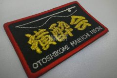 メタリックゴールドの糸でチーム名を真ん中に刺繍し、上下に釣り竿のイラストや釣り方などを刺繡した、オリジナル刺繡ワッペンの制作事例。