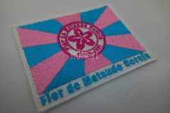 ショッキングピンクでサンバチームのロゴを中心にしたピンクと水色の旗と下部にチーム名を刺繡した、オリジナル刺繡ワッペンの制作事例。