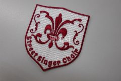 盾形の形状でフローラルデザインと校章がミックスしたロゴ刺繍ワッペン。刺繍糸色はエンジカラー単色。