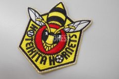 蜂のデザインが上部中央に縫われた、野球チームの刺繍ワッペン。ベース生地はイエローのエンブクロス。