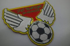 サッカーボールに羽が生えているようにも見え、またキーパーの手がボールを止めているようにも見えるユニークな刺繡ワッペンの制作事例。