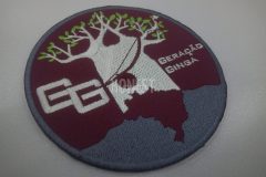 えんじ色の円形ワッペンに白い木と人物のシルエットが描かれ、『GG』『GERAÇÃO GINGA』の文字が刺繍されたオリジナル刺繡ワッペンの制作事例。