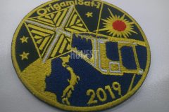 黒色の生地に黄色の糸で小型衛星と日本列島を刺繡した、刺繡ワッペンの制作事例。