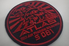 黒色の生地に赤色の糸で2匹の鷲のイラストと集団名を刺繡したオリジナル刺繡ワッペンの制作実績。