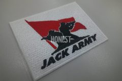 なびく赤い旗の前で背中合わせで共闘しているシルエットが刺繡されたオリジナル刺繡ワッペンの制作実績。