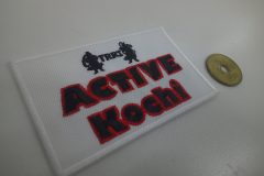 白色の生地に黒と赤色の糸で団体名を刺繍した長方形のオリジナル刺繡ワッペンの制作実績。