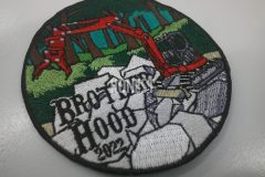 森の激しい岩場の中に目立つ赤い重機が描かれた刺繍のオリジナル刺繡ワッペンの制作実績。