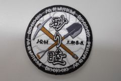 つるはしとスコップのイラストと団体名が目立つオリジナル刺繡ワッペンの制作実績。