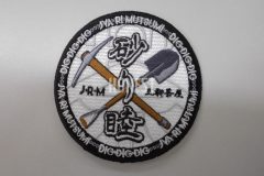 つるはしとスコップのイラストと団体名が目立つオリジナル刺繡ワッペンの制作実績。