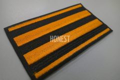 黒色の生地にオレンジ色の刺繍糸で4本のラインを刺繡したオリジナル刺繡ワッペンの制作実績。