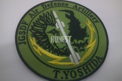 アーミー色のツイル生地ライオンの顔の右側半分と銃弾のイラストの刺繡をした、オリジナル刺繡ワッペンの制作実績。