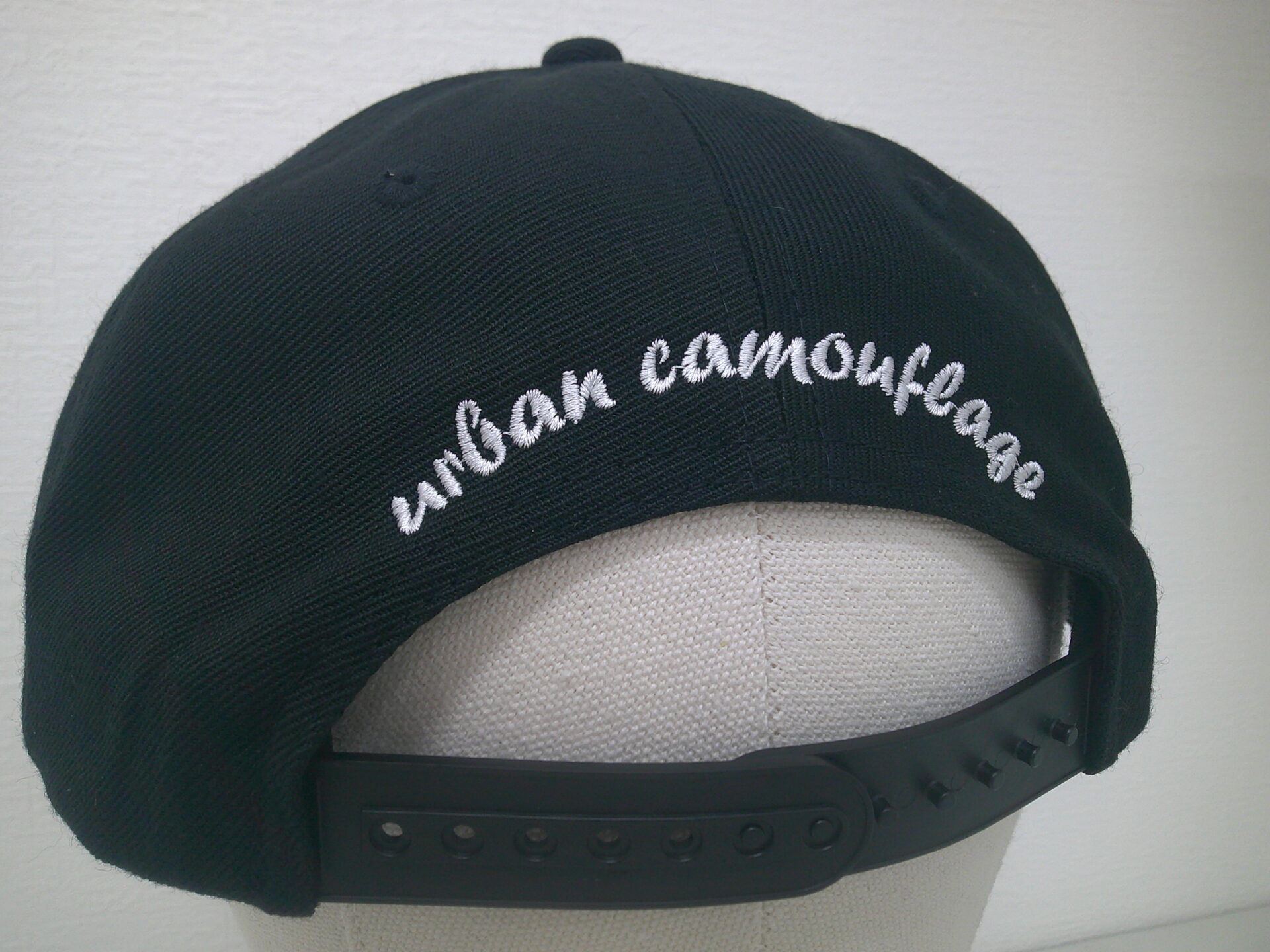 帽子背面に筆記体・白糸で文字を刺繍した制作事例。