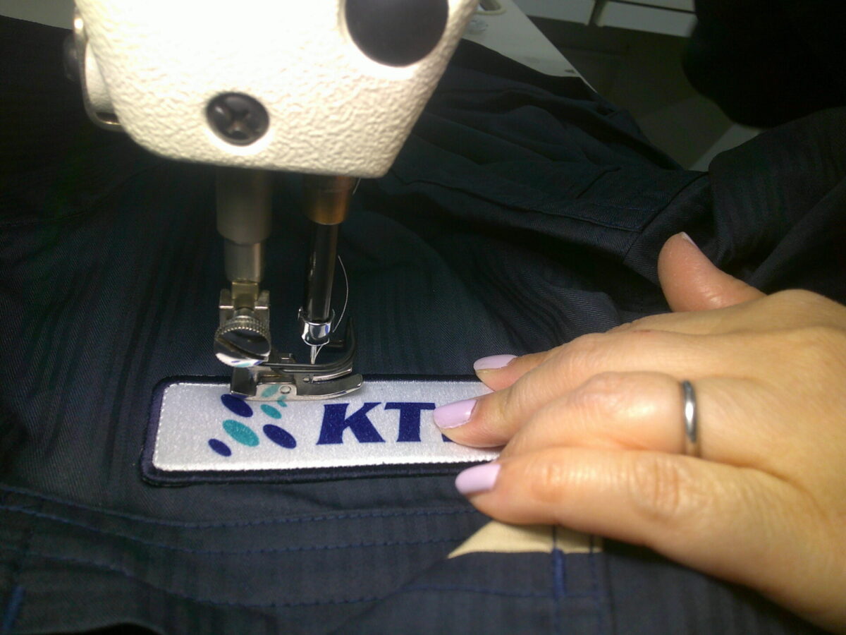 ワッペンを工業用ミシンで縫い付けている作業工程。