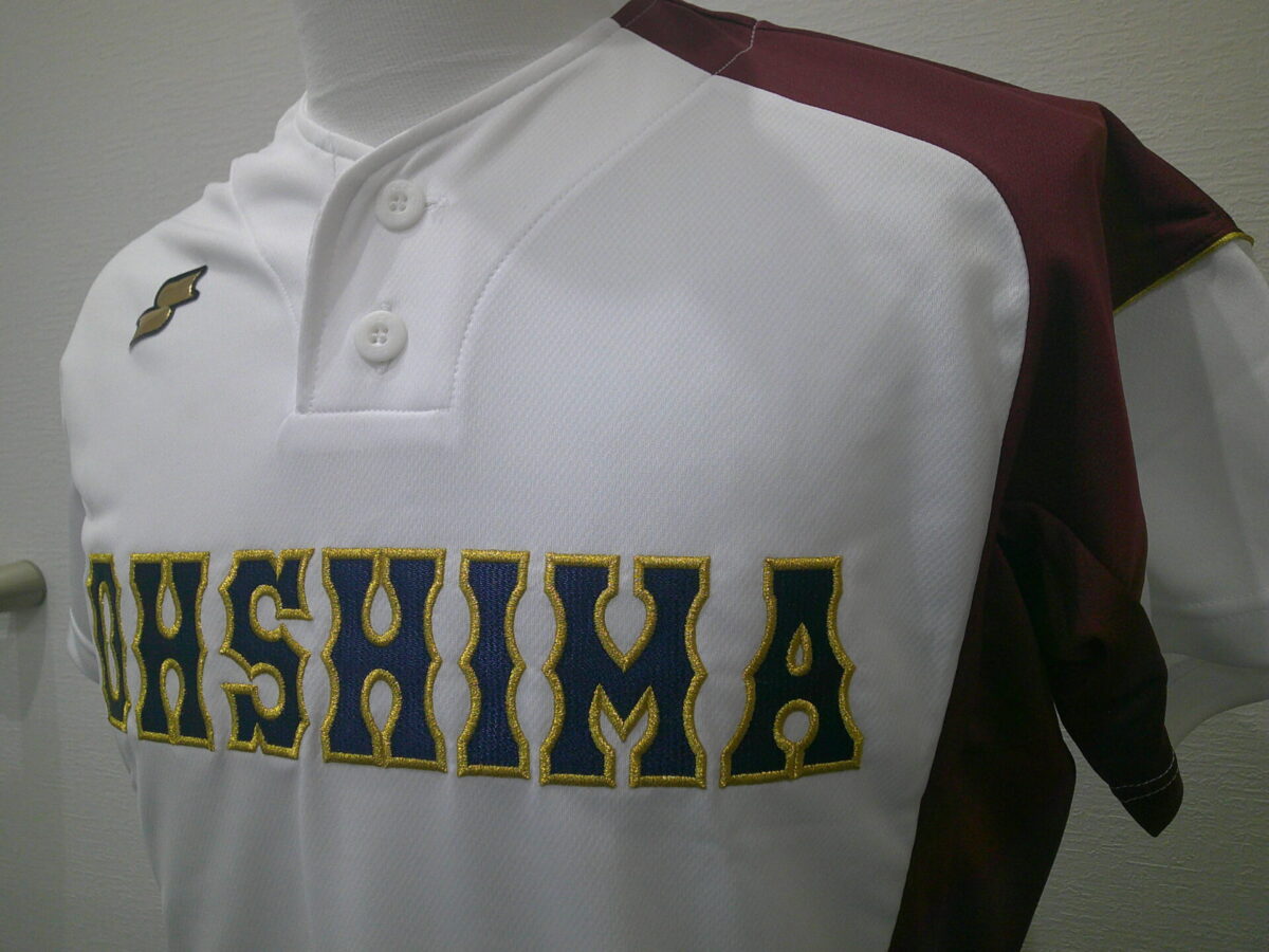 白ユニフォームの前面に「OHSHIMA」と縁取り刺繍をした制作実績。紺のエンブクロスに金糸で縁取り。