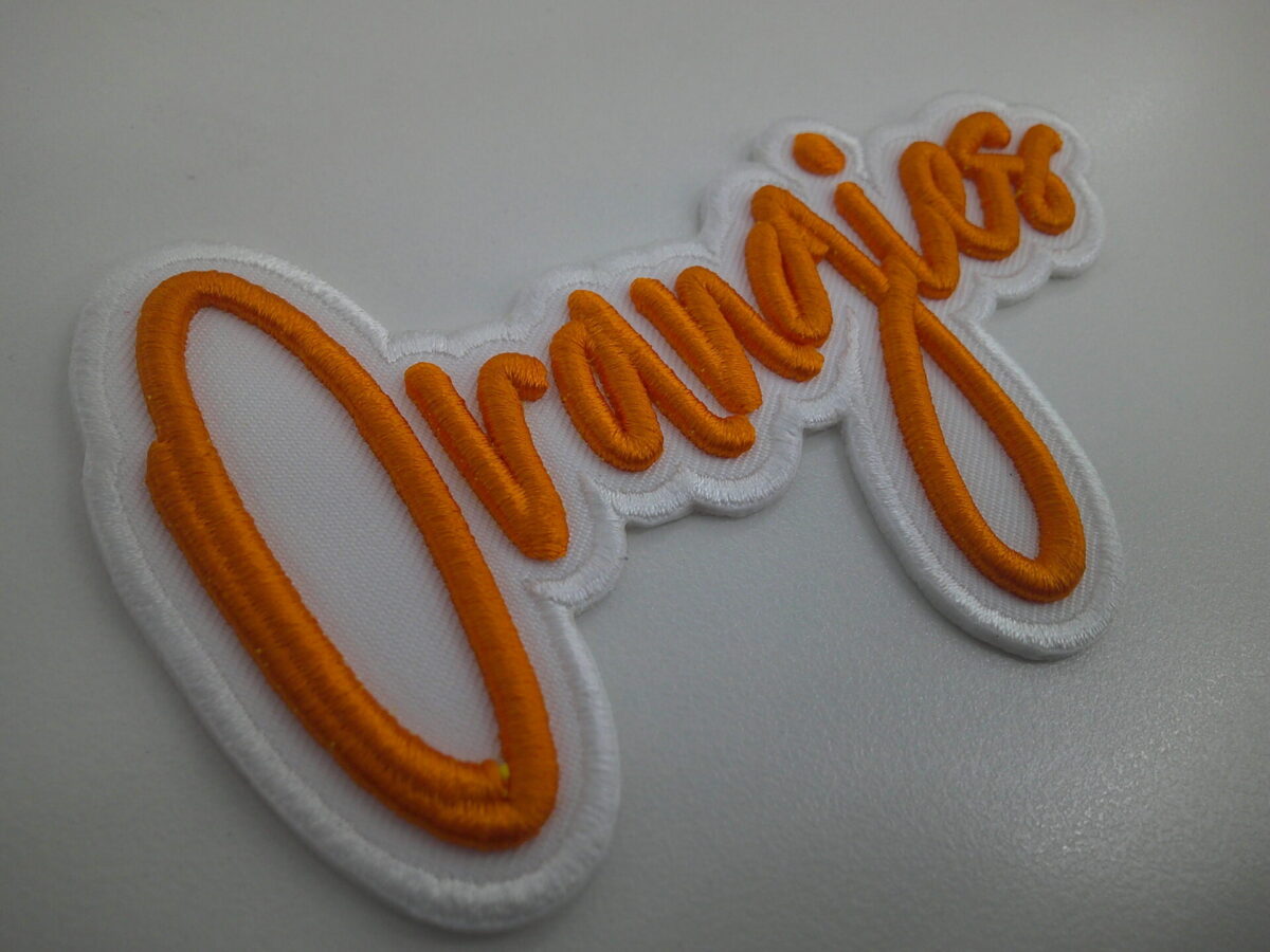 オレンジの文字を3D刺繍として製作した3D刺繍ワッペン。ベース生地は白のアーバンツイル。