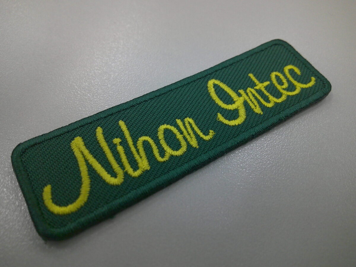 ゴルフスクール名を緑の生地に黄色の糸で縫った、もったいないワッペンの制作事例。