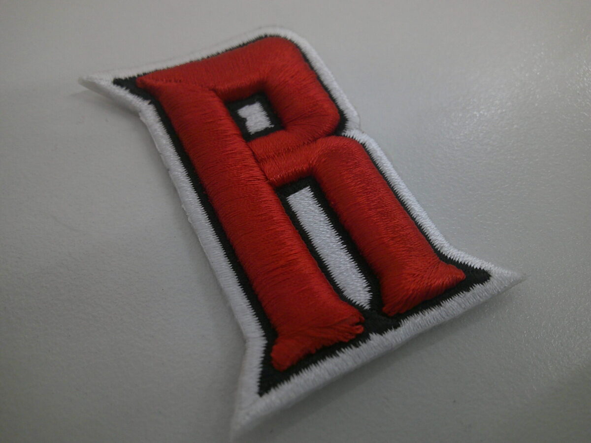 「R」の文字を3D刺繍ワッペンとして製作。赤文字に白フチ。