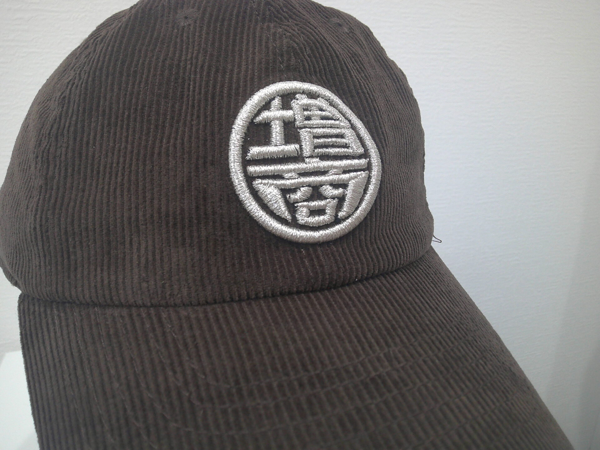 コーデュロイキャップフロントに銀糸で会社様ロゴを3D刺繍した作品。