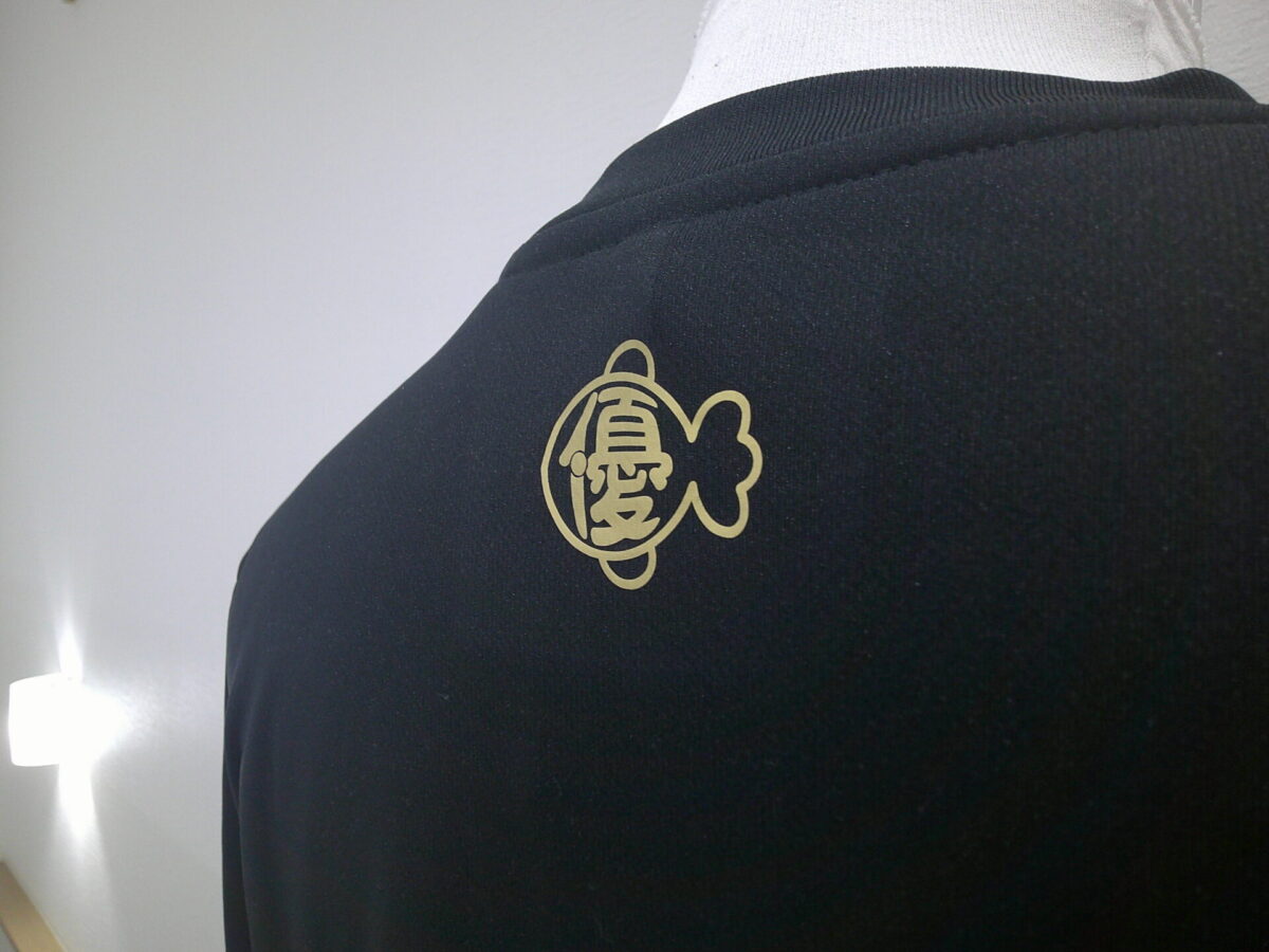 金魚のロゴデザインをゴールドカラーのラバーシートでラバープリントした加工部分のアップ。